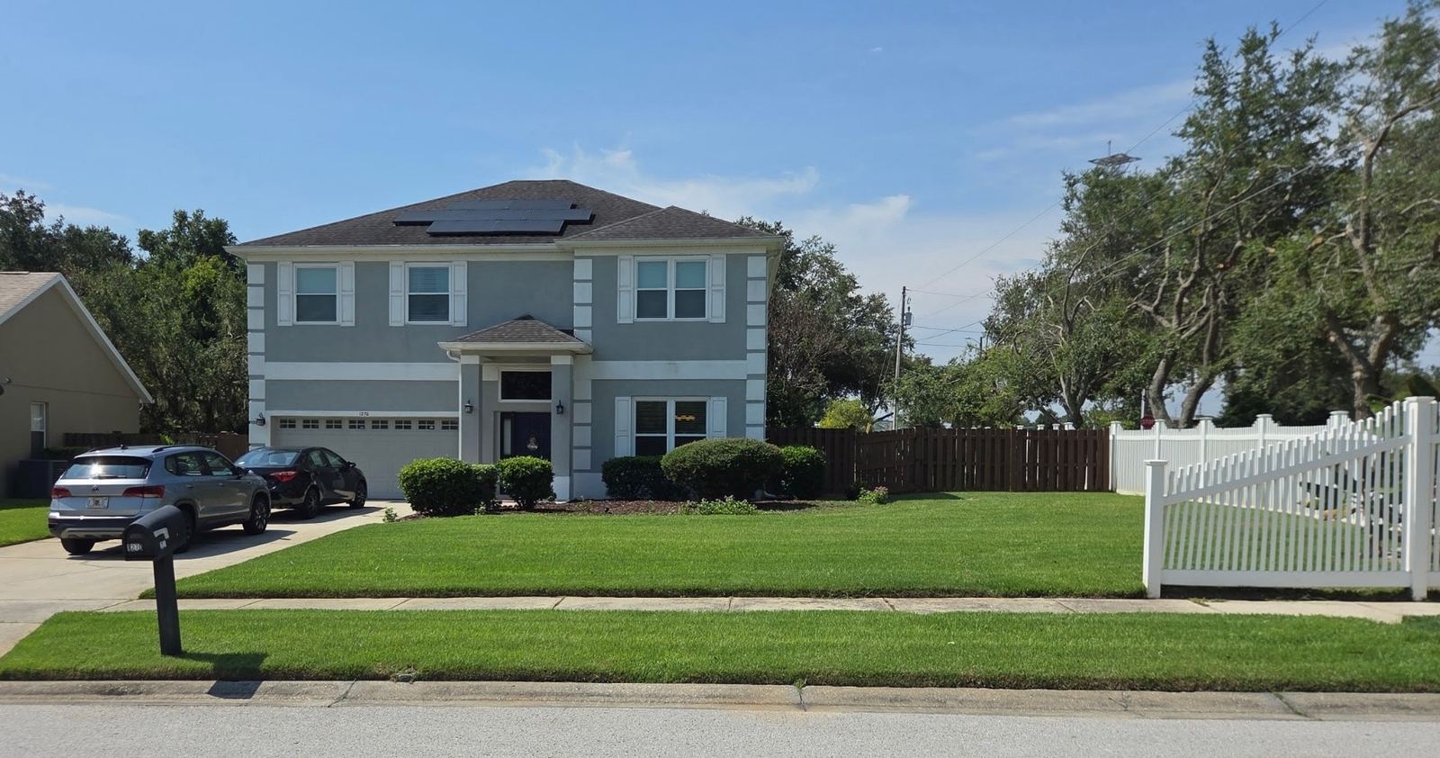 Two-story Central Florida home with a manicured lawn and white picket fence